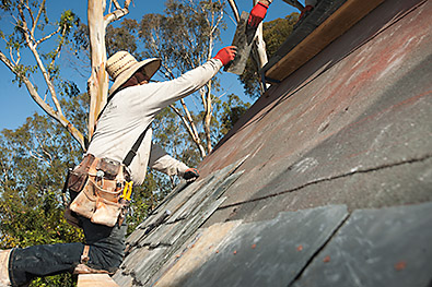 Roofers install slate on steep roof