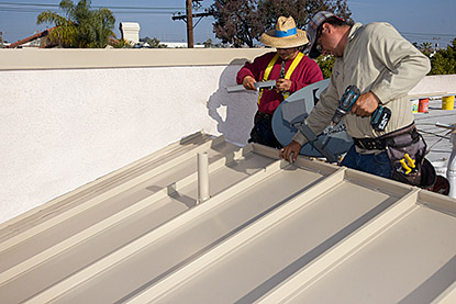 Roofers install the top trim metal.
